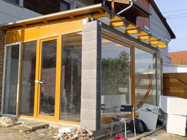 Télikert építése Pécsen diófóliás műanyag nyílászárókkal, hőszigetelt üveg toló-bukó ajtóval és üvegtetővel, RID Solutions Kft. kivitelezés.